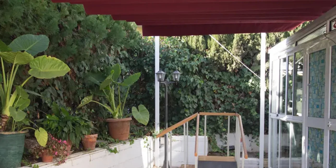 Persona mayor paseando acompañada por el patio de una residencia