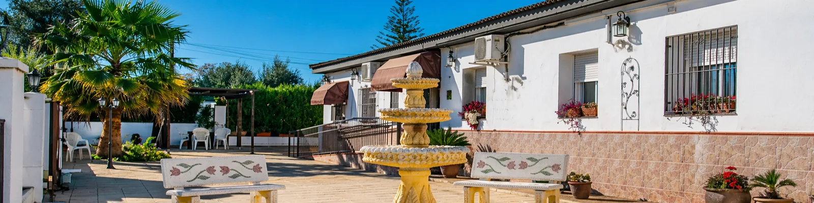 Patio del Centro de Mayores Fuente Clara en Palomares del Río, con fuente y zona de estar al aire libre